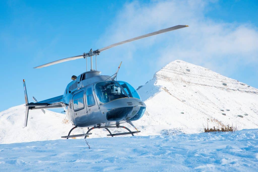 Helicopter landing in snow with snow covered mountain in the back