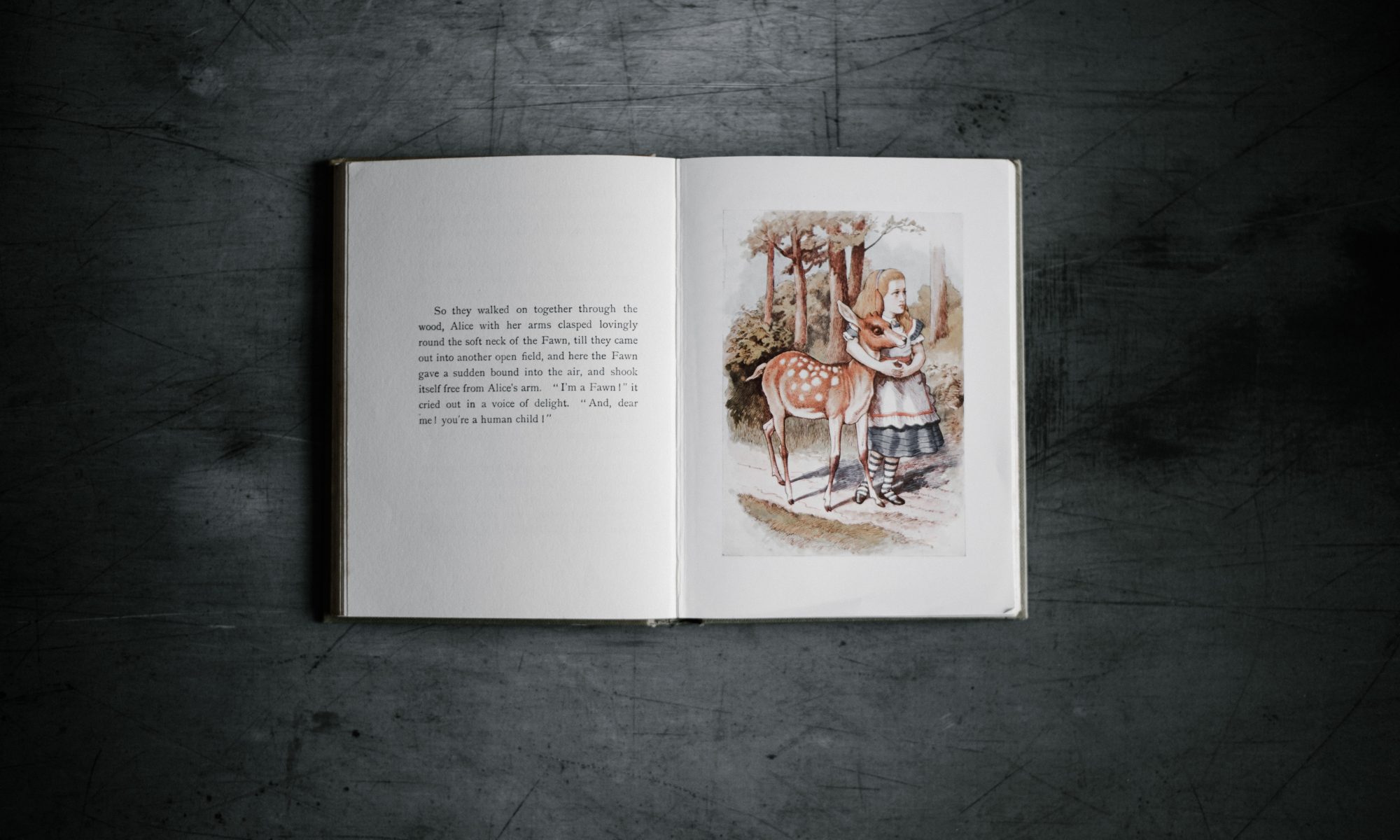 open Alice in Wonderland book with text and Alice with a deer